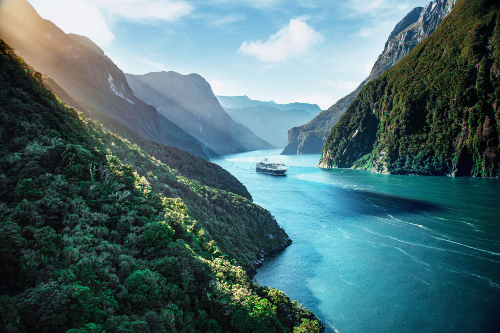 Carnival cruise ship sailing through a narrow fjord surrounded by mountains.